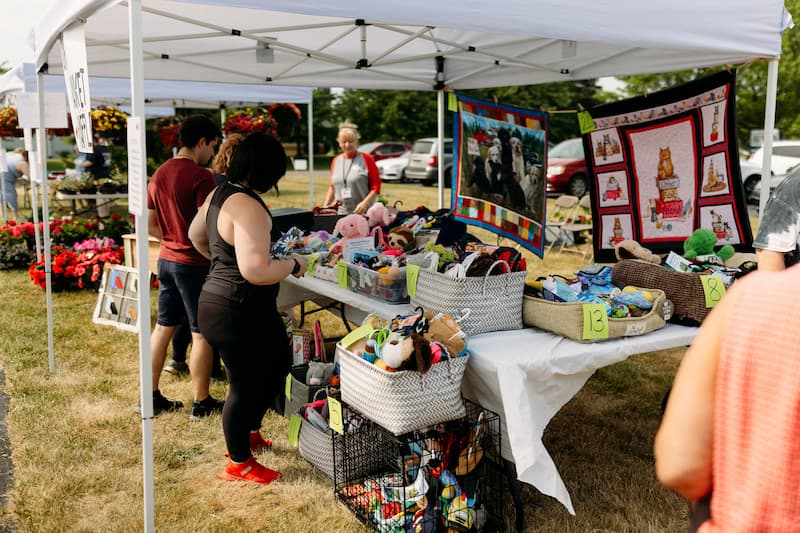 People at a booth with baskets full of pet supplies during a community event